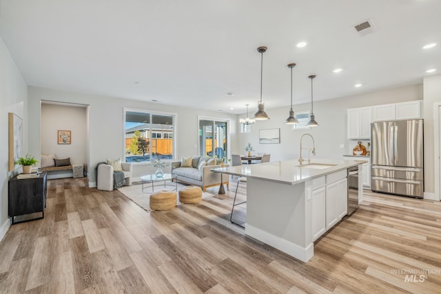 kitchen featuring sink, white cabinets, a kitchen island with sink, and appliances with stainless steel finishes