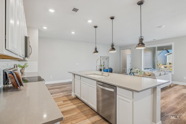 kitchen with stainless steel appliances, sink, decorative light fixtures, white cabinets, and an island with sink