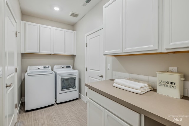 clothes washing area with washer and dryer and cabinets