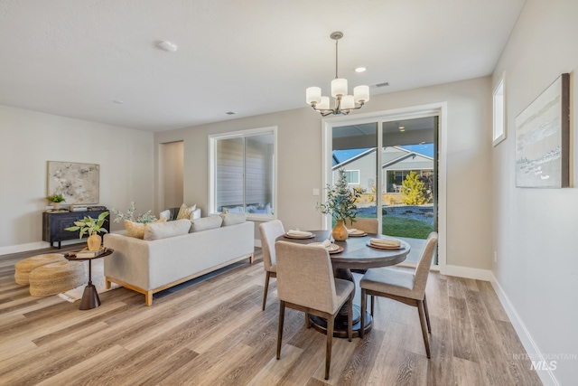 dining space with light hardwood / wood-style floors and a notable chandelier