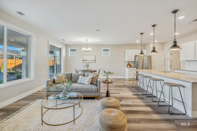 living room featuring a notable chandelier, wood-type flooring, and sink