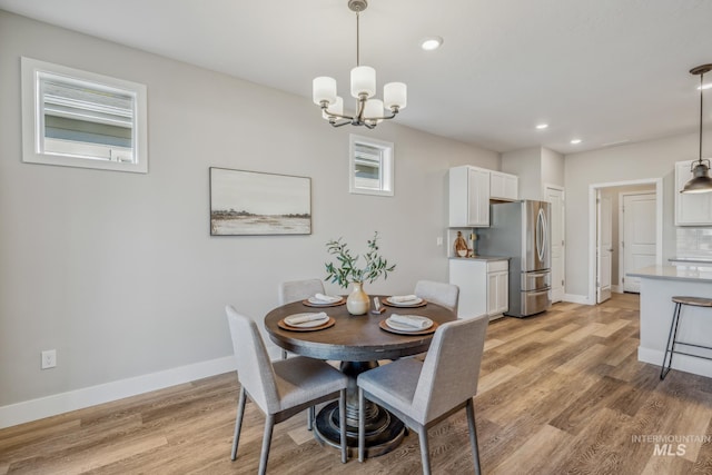 dining space with light hardwood / wood-style floors and a chandelier