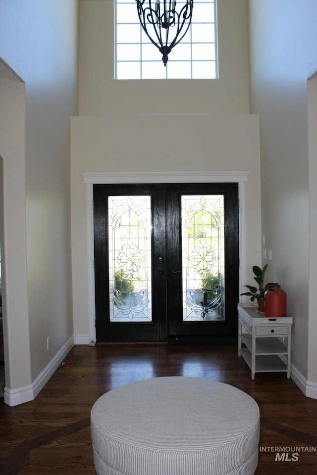 foyer entrance with french doors, a towering ceiling, dark hardwood / wood-style floors, and plenty of natural light