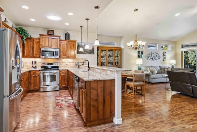 kitchen with pendant lighting, backsplash, a breakfast bar area, kitchen peninsula, and stainless steel appliances