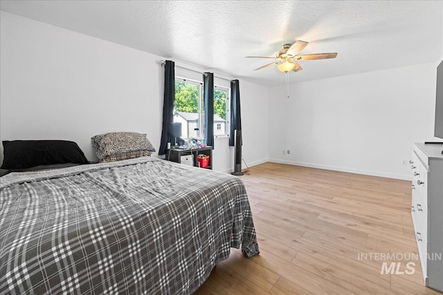 bedroom with baseboards, ceiling fan, a textured ceiling, and light wood-style flooring