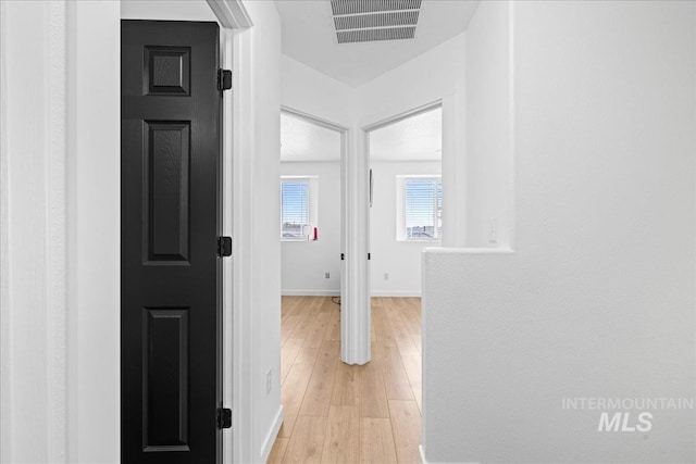 corridor with baseboards, visible vents, and light wood-type flooring