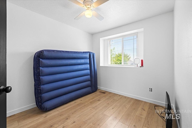 bedroom with baseboards, a ceiling fan, wood finished floors, and visible vents