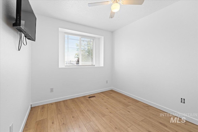 unfurnished room featuring light wood-style floors, baseboards, a ceiling fan, and visible vents
