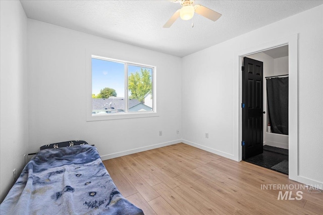 unfurnished bedroom with connected bathroom, baseboards, ceiling fan, and wood finished floors