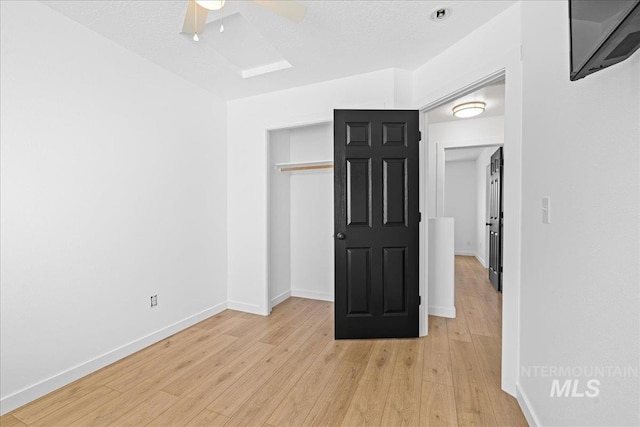 empty room with a ceiling fan, baseboards, and light wood finished floors