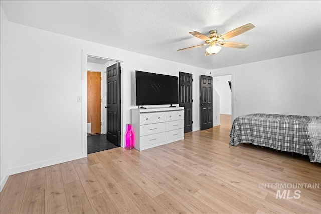bedroom featuring baseboards, a ceiling fan, a textured ceiling, and light wood-style flooring