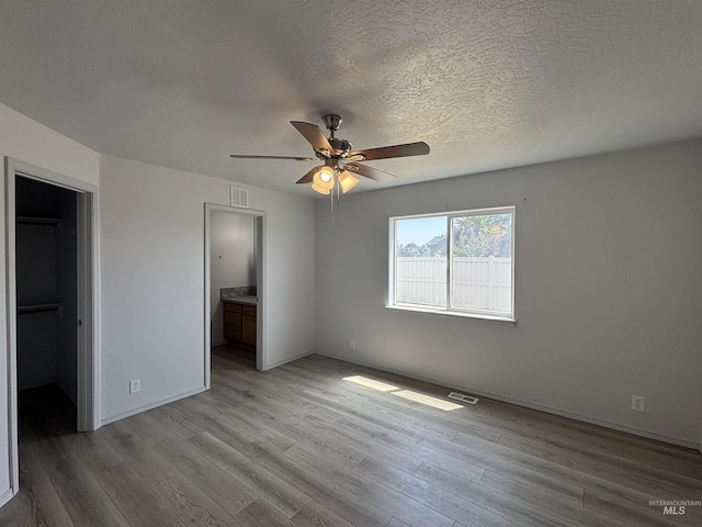 1150 NW 22nd St, Fruitland, ID 83619 - unfurnished bedroom with light wood-type flooring, connected bathroom, a textured ceiling, and a ceiling fan
