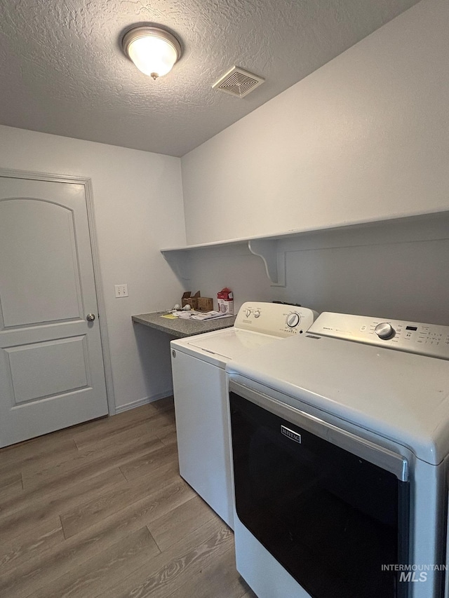 1150 NW 22nd St, Fruitland, ID 83619 - washroom featuring independent washer and dryer, a textured ceiling, and light wood-style flooring