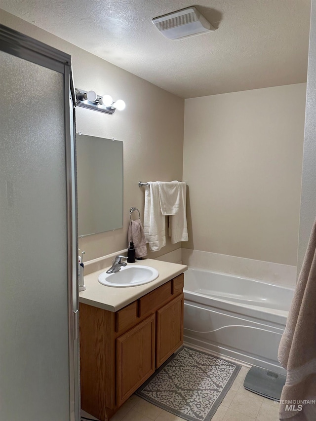 168 Long Is, Twin Falls, ID 83301 - bathroom featuring vanity, tile patterned flooring, a textured ceiling, visible vents, and a garden tub