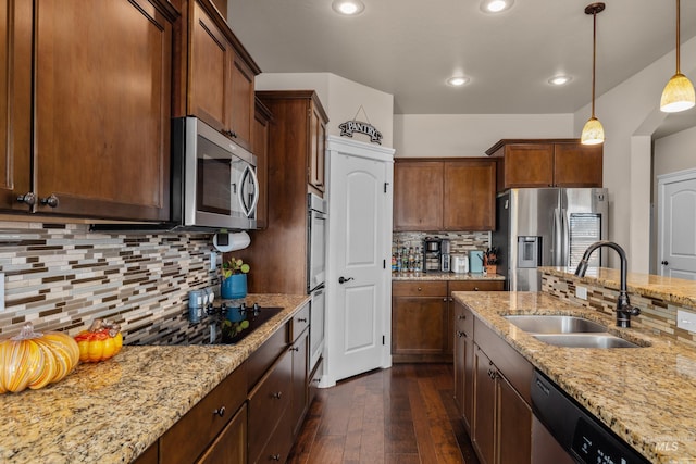 kitchen with light stone countertops, sink, stainless steel appliances, dark hardwood / wood-style floors, and pendant lighting