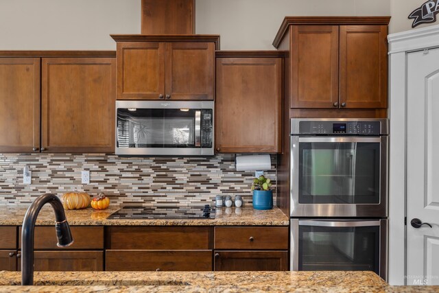 kitchen featuring light stone countertops, appliances with stainless steel finishes, tasteful backsplash, and sink