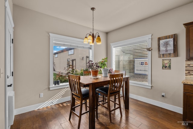 dining area with a chandelier, plenty of natural light, and dark wood-type flooring