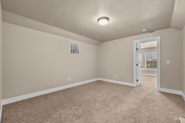 additional living space featuring a textured ceiling, light colored carpet, and lofted ceiling