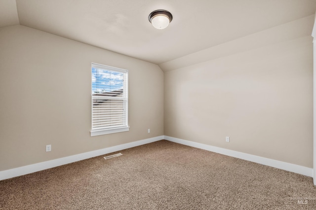 spare room with carpet and vaulted ceiling