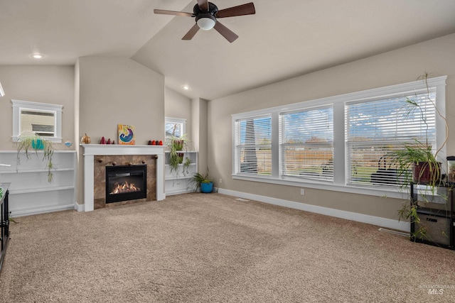 carpeted living room featuring a tiled fireplace, ceiling fan, plenty of natural light, and lofted ceiling