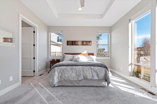 carpeted bedroom with ceiling fan and a tray ceiling