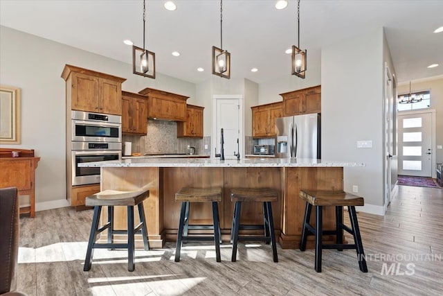 kitchen featuring appliances with stainless steel finishes, a large island, pendant lighting, and a kitchen breakfast bar