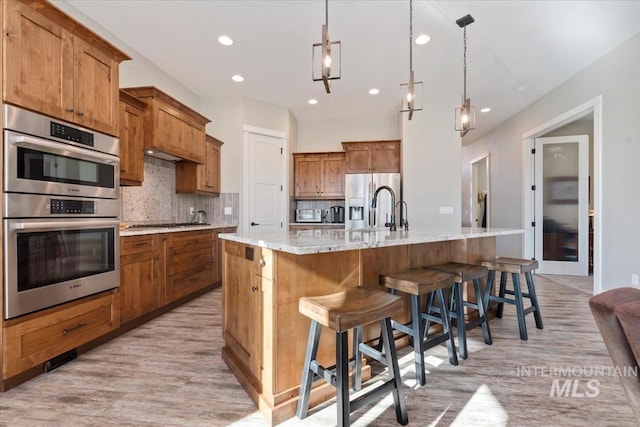 kitchen featuring appliances with stainless steel finishes, a large island, a kitchen breakfast bar, and decorative light fixtures