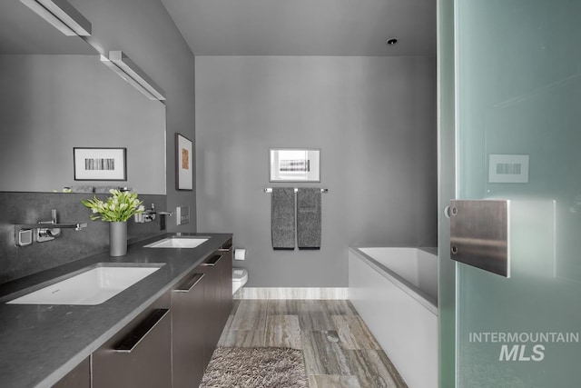 bathroom featuring a bathing tub, hardwood / wood-style floors, vanity, and toilet