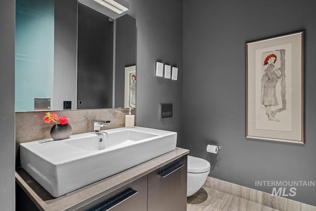 bathroom featuring vanity, toilet, and decorative backsplash