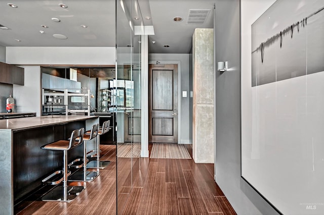 kitchen featuring a breakfast bar, stainless steel oven, and wood-type flooring