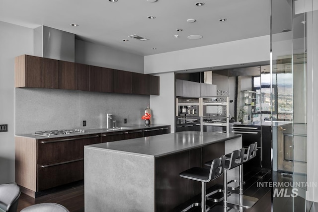 kitchen with a kitchen island, stainless steel appliances, backsplash, a breakfast bar, and dark hardwood / wood-style flooring