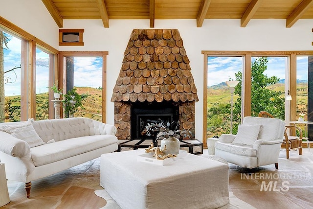 living room featuring wood ceiling, beamed ceiling, and a stone fireplace