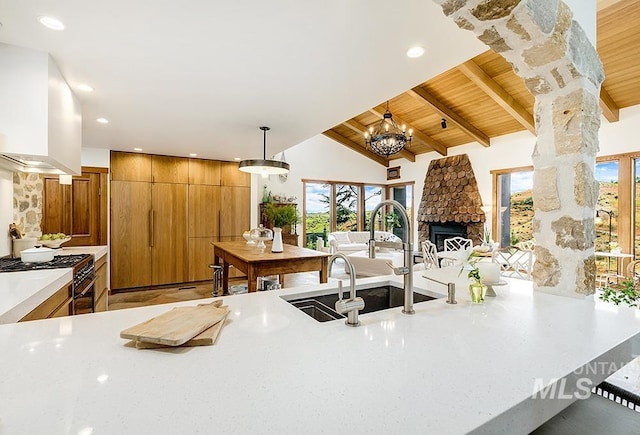 kitchen featuring a fireplace, decorative light fixtures, vaulted ceiling with beams, wood ceiling, and range