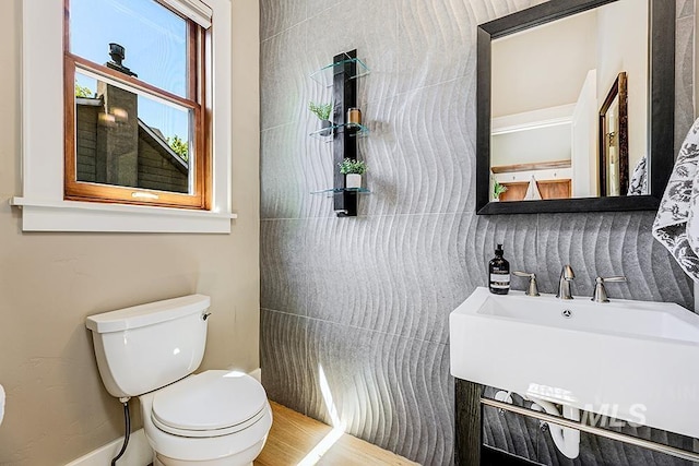 bathroom with toilet, a sink, and wood finished floors