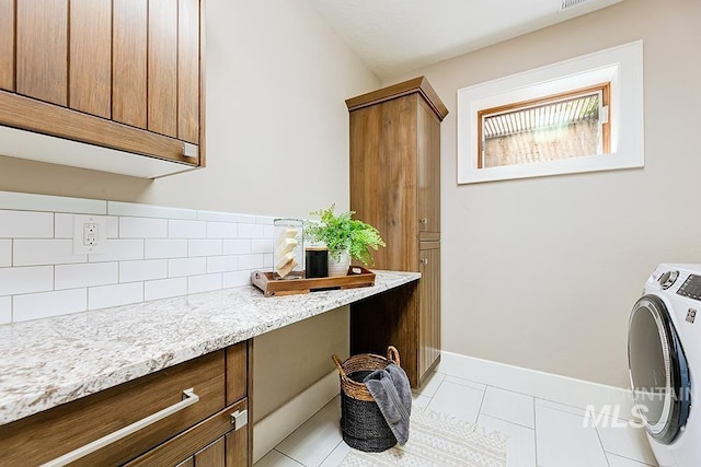 laundry room with washer / clothes dryer, light tile patterned flooring, cabinet space, and baseboards