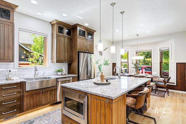 kitchen with appliances with stainless steel finishes, light wood-type flooring, a sink, and recessed lighting
