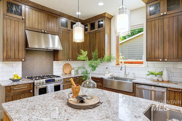 kitchen featuring under cabinet range hood, appliances with stainless steel finishes, a sink, brown cabinetry, and recessed lighting