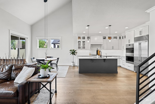 living room featuring light wood-style floors, baseboards, high vaulted ceiling, stairway, and recessed lighting