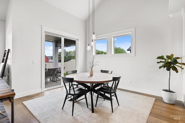 dining area with baseboards, wood finished floors, vaulted ceiling, and visible vents