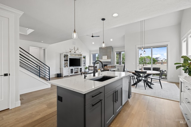 kitchen featuring open floor plan, gray cabinetry, a sink, and light wood-style flooring