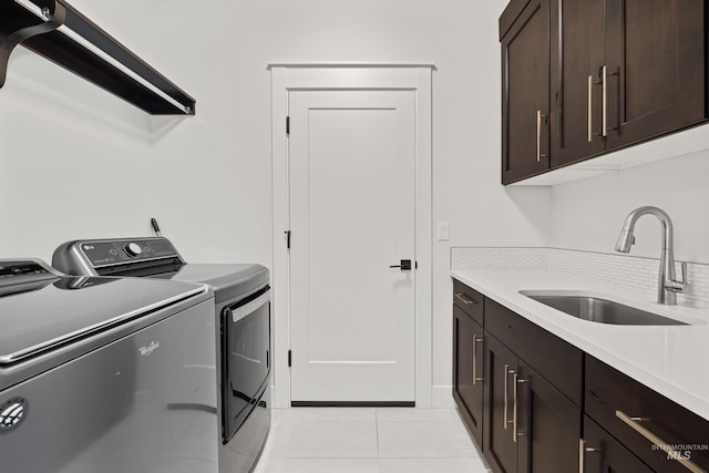 laundry area with cabinet space, separate washer and dryer, light tile patterned flooring, and a sink