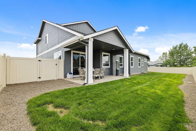 rear view of house featuring a gate, a patio area, a fenced backyard, and a yard