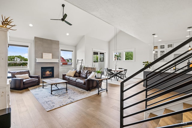 living room with ceiling fan, a wealth of natural light, stairway, and a fireplace