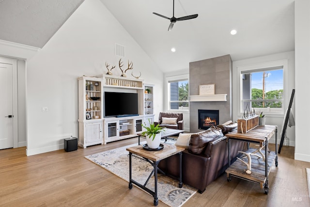living room featuring a ceiling fan, visible vents, a healthy amount of sunlight, and a tile fireplace
