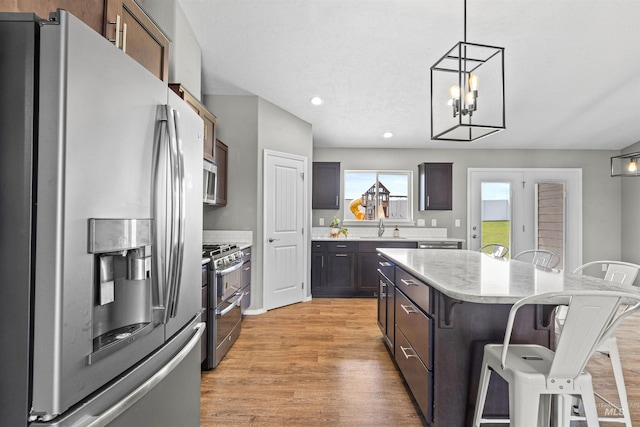 1724 Pioneer Dr, Lewiston, ID 83501 - kitchen featuring stainless steel appliances, a breakfast bar, a kitchen island, light wood finished floors, and decorative light fixtures