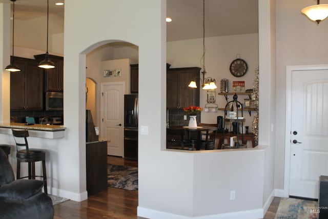 4951 W Torana St, Meridian, ID 83646 - kitchen featuring stainless steel microwave, dark wood-style floors, dark brown cabinetry, black fridge with ice dispenser, and arched walkways