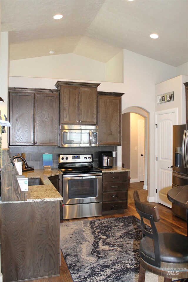 4951 W Torana St, Meridian, ID 83646 - kitchen featuring appliances with stainless steel finishes, vaulted ceiling, a sink, dark brown cabinetry, and arched walkways
