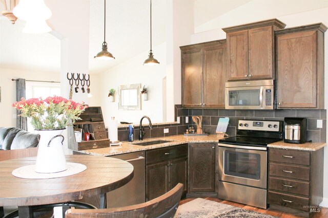 4951 W Torana St, Meridian, ID 83646 - kitchen featuring appliances with stainless steel finishes, a sink, tasteful backsplash, lofted ceiling, and light stone countertops