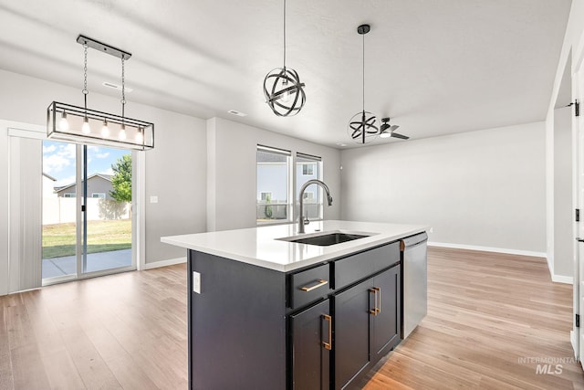 1755 N Crystal Cove Ave, Meridian, ID 83646 - kitchen with stainless steel dishwasher, light countertops, light wood finished floors, and a center island with sink