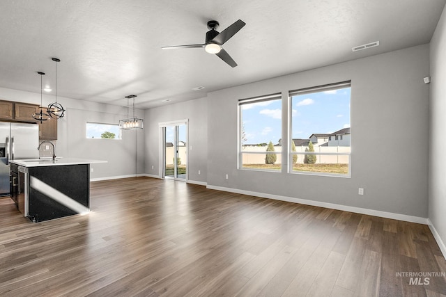 1755 N Crystal Cove Ave, Meridian, ID 83646 - unfurnished living room featuring ceiling fan, dark wood-style floors, and a chandelier
